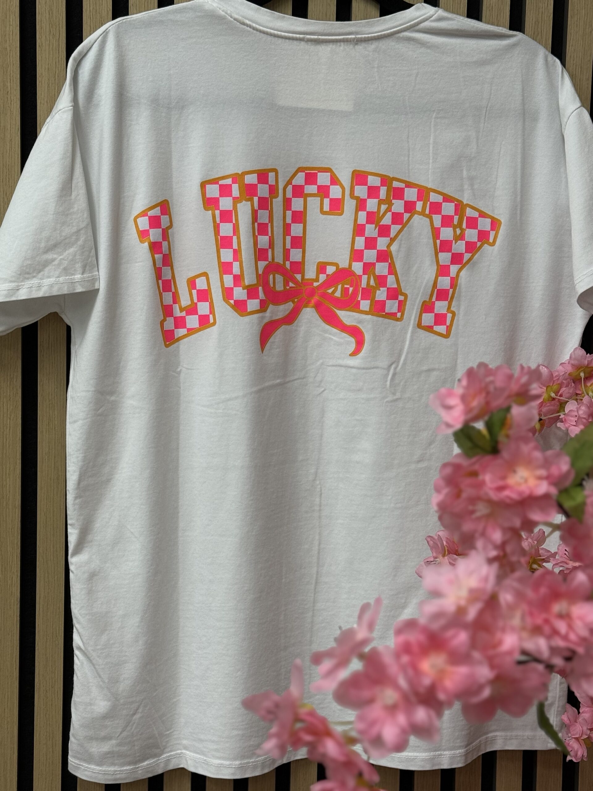 Wit T-shirt met felroze strikje en Lucky backprint | So Lucky Wit T-shirt met felroze strikje en Lucky backprint | So Lucky