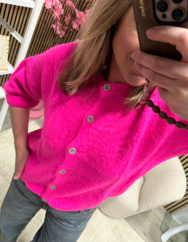 Model draagt gebreid vest Britt neon roze met een jeans – So Lucky