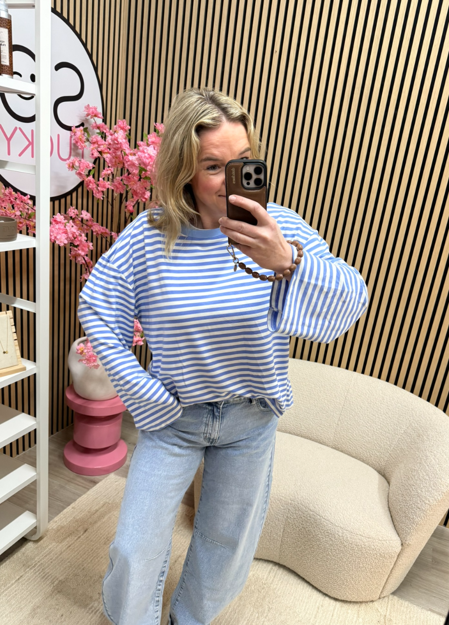 model draagt gestreepte longsleeve Maud blauw ecru op lichte jeans voor de spiegel – So Lucky