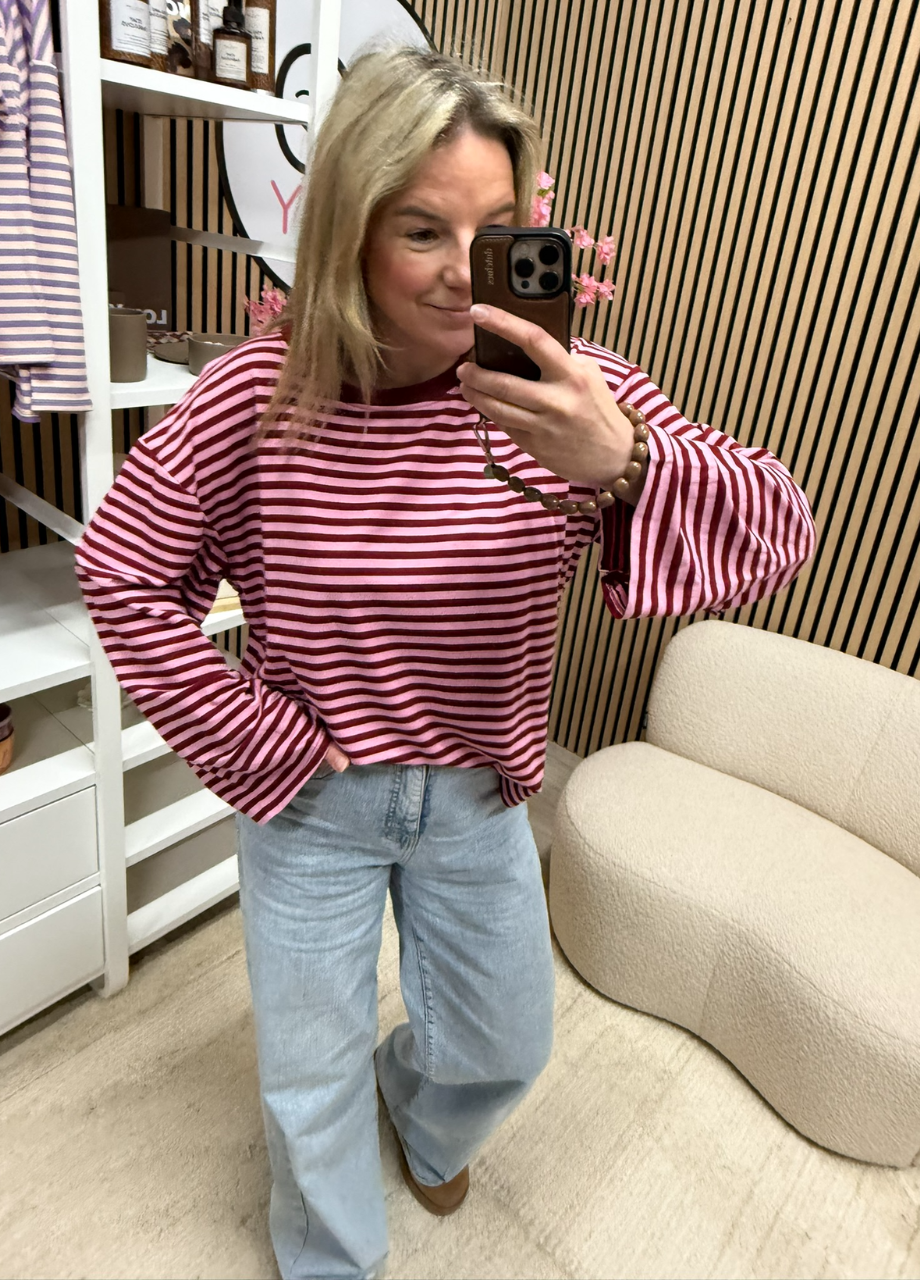 model draagt gestreepte longsleeve Maud bordeaux roze oversized langer model op een jeans – So Lucky