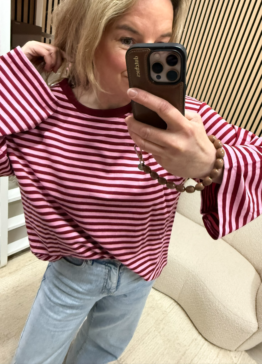 model draagt gestreepte longsleeve Maud bordeaux roze oversized langer model casual op een jeans – So Lucky