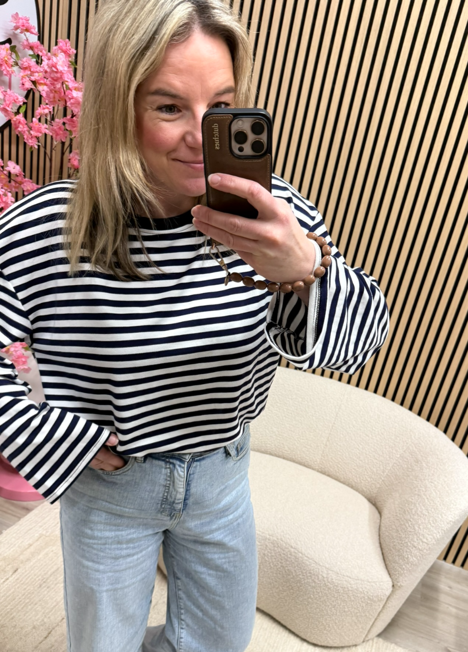 model draagt gestreepte longsleeve Maud donkerblauw wit oversized langer model casual op een jeans – So Lucky