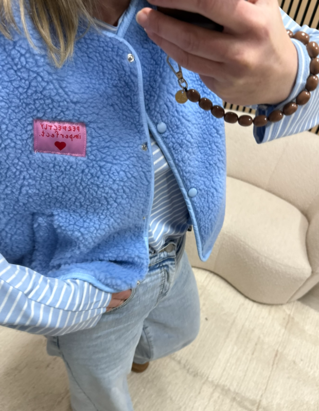 model draagt teddy bodywarmer blauw Perfectly imperfect patch over een gestreepte top op een jeans – So Lucky