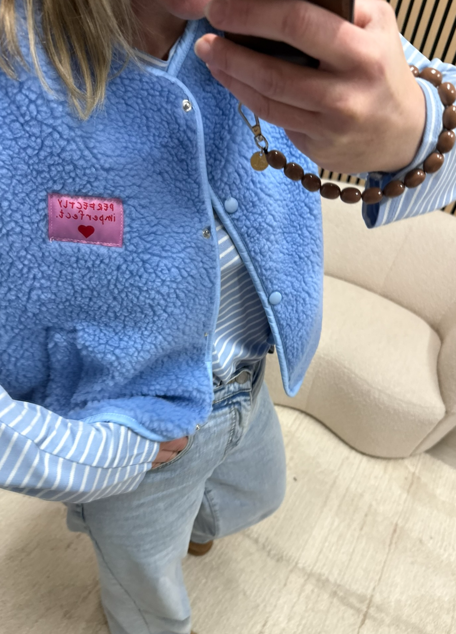 model draagt teddy bodywarmer blauw Perfectly imperfect patch over een gestreepte top op een jeans – So Lucky