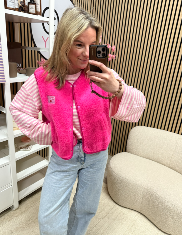 model draagt teddy bodywarmer roze Perfectly imperfect patch over een gestreepte top en jeans – So Lucky