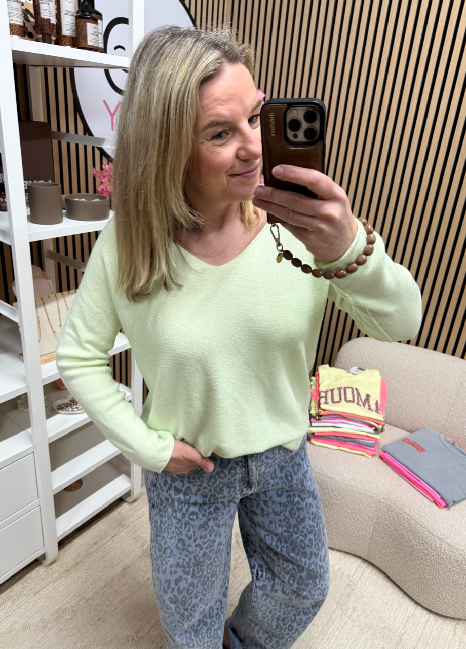 model draagt fijngebreide top lichtgroen diepe V-hals iets ingestopt in een jeans – So Lucky