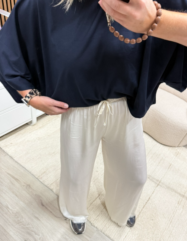 Model draagt ecru pantalon met zijde gecombineerd met een donkerblauwe top - So Lucky